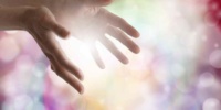 Woman's outstretched healing hands with light bokeh background and energy ball